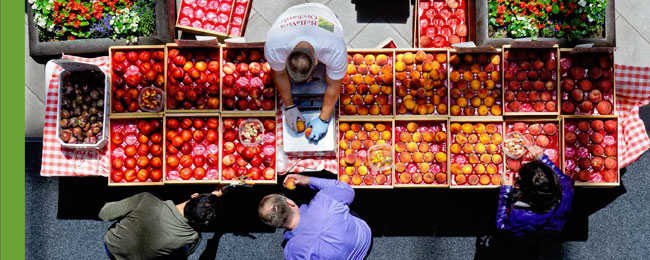 Overhead photograph of a farmrers market fruit stand full of peaches and produce.