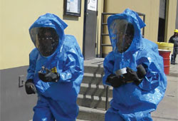 Two trainees wearing blue hazardous materials (HAZMAT) suits walking side by side.