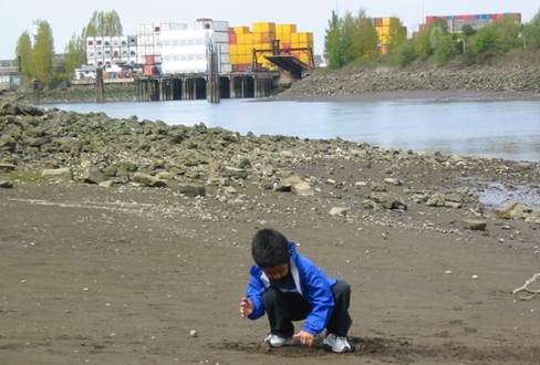Kids playing in sand next to an urban waterway