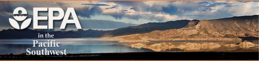 Lake shore with desert landscape, low mountain ranges, and rainclouds