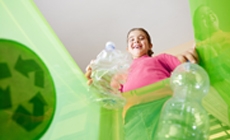 photo of girl throwing bottle in recycle bin