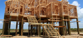 Stilts are added to the framework of a house on the beach