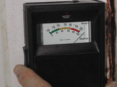 Moisture meter, showing high moisture content in gypsum board behind tile.