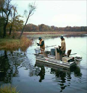 Two men in a boat studying chemical residue on lake fish
