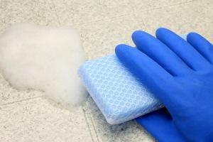 Photo of gloved hand using scrub to clean surface