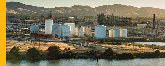Refinery/Chemical facility alongside a river with golden hills in background: Photo: California Department of Water Resources