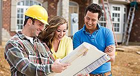 Contractor with hard hat looking at blue prints with husband and wife