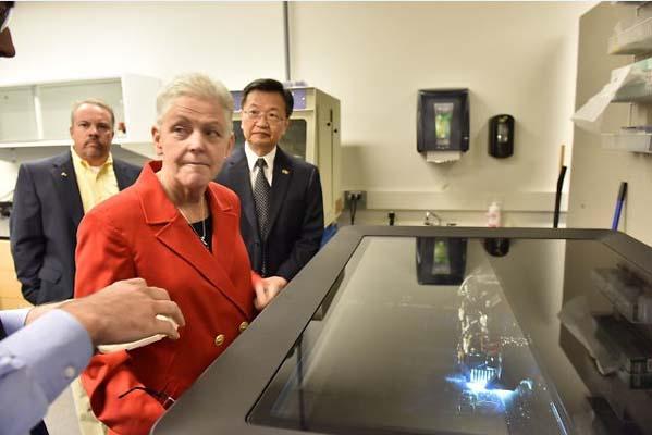 Administrator McCarthy at the glassy surface of a machine.