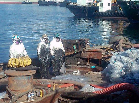 workers covered in oil after removing almost 18,000 lbs. of asbestos found on the vessel
