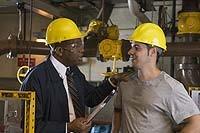 This is a picture of two men in hard hats in an industrial plant