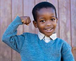 Young boy showing his muscles wearing a blue sweater