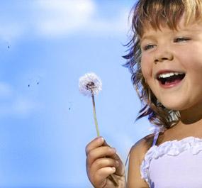 Young girl laughing and holding a dandelion