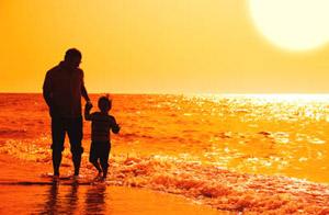 Father and son walking on beach at sunset