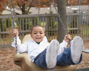 Young boy smiling while swinging on a swing set