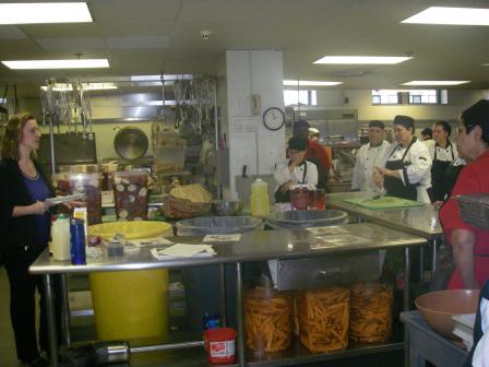 photo of several people in a Clark University dining hall kitchen discussing reducing wasted food