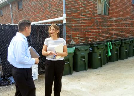 Woman and man standing next to recycling bins