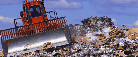 A tractor piling up trash in a landfill