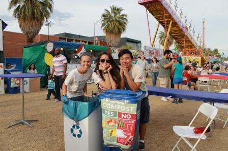 this is a picture of three young people standing over a recycling bin and a compost bin