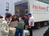 Truck with 'Food Runners' painted on the side being loaded with food.