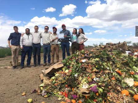 Students and University of Arizona employees standing near a large pile of compostable food waste.