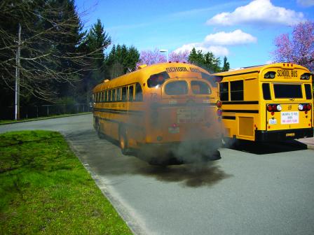 Yellow school bus with cloud of black soot coming from exhaust