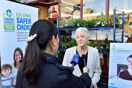 EPA Administrator Gina McCarthy being interviewed with 'Safer Choice' poster in background.