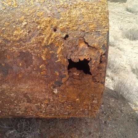 Closeup of rusted steel underground storage tank showing complete rust through of tank (multiple rust encrusted holes through the tank)