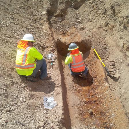 Workers taking samples from exposed trench.