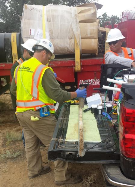 Technicians using equipment to test a soil core for radiation contamination