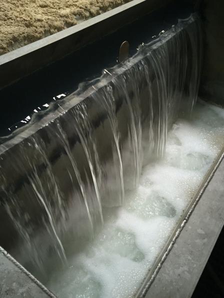 Waterfall of clear water emerging from slurry tank making foam.
