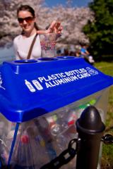 Woman recycling plastic in blue bin