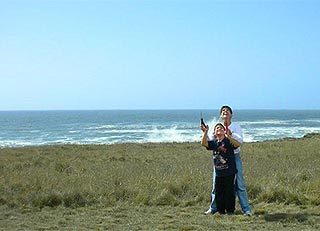 two boys flying a kite near the ocean