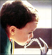 A boy drinking from a water fountain