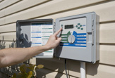 A homeowner sets his or her irrigation controller to save water outdoors.